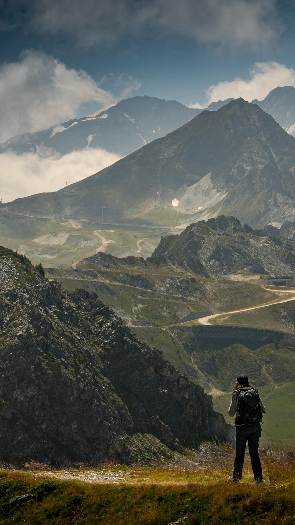 A hiker captures the breathtaking view of rugged mountains under a dramatic sky.